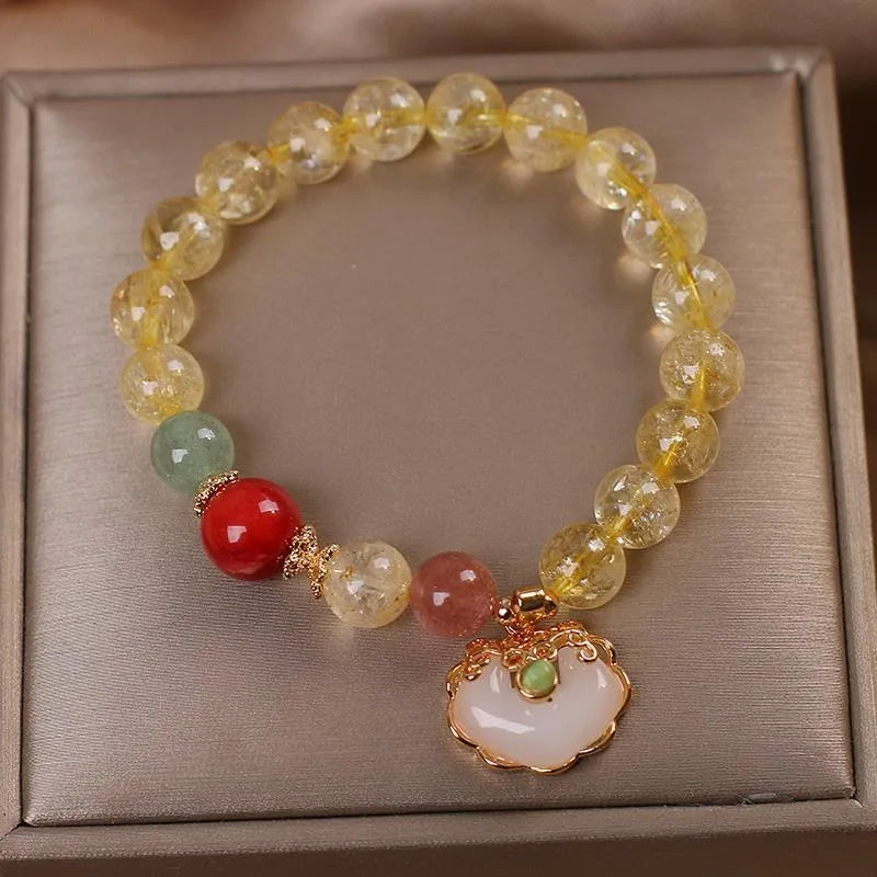Women's yellow alloy bracelet with a ruyi pendant charm holding natural citrine and yellow hair crystal jade.
