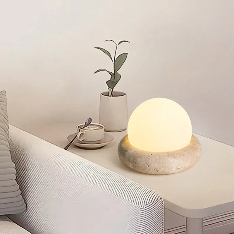 Cream-coloured modern bedside night light with remote control on a table.