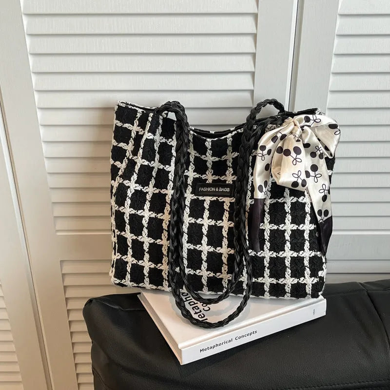 Black woven wool shoulder bag showing horizontal square shape and external pocket.