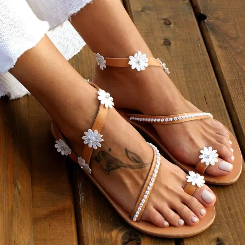 Brown women's Roman sandals with flat rubber soles, floral decoration, and herringbone toe shaping