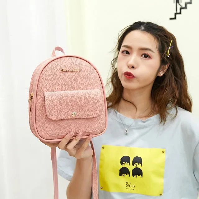 Small black PU leather women's shoulder backpack with a zipper, shown next to a mobile phone for scale.
