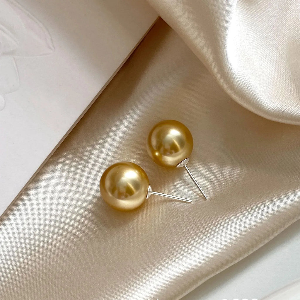 A pair of large geometric pearl stud earrings with an eight-awn star detail on silver settings.