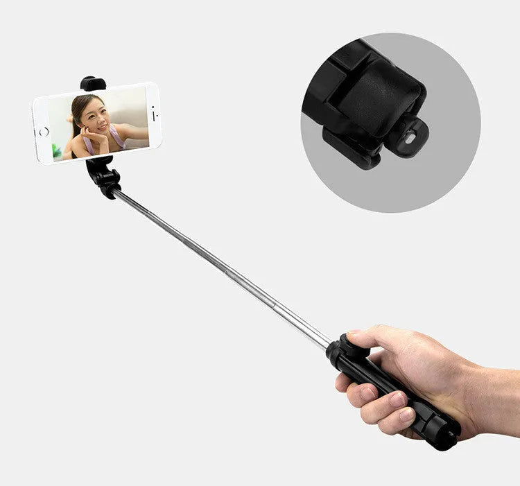 Apple-compatible black tripod selfie stand with Bluetooth remote and 360-degree rotating phone clip extended.