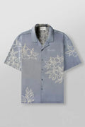 Man wearing a loose grey short-sleeve top with a floral print pattern.
