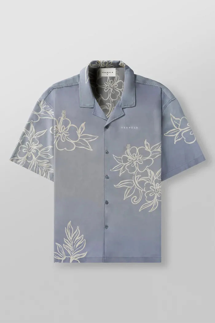 Man wearing a loose grey short-sleeve top with a floral print pattern.