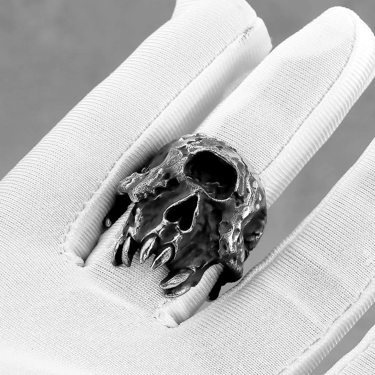 Close-up of a silver-toned alloy ring featuring a detailed one-eyed skull design on a black background.