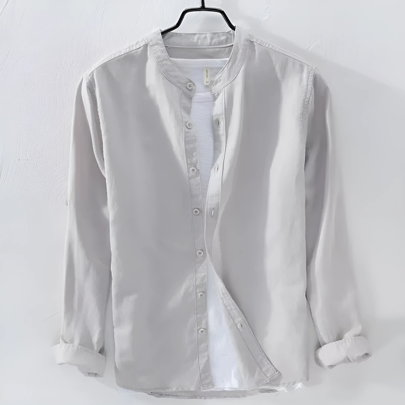 Man's loose fitting long sleeve linen shirt in a solid colour on a hanger.