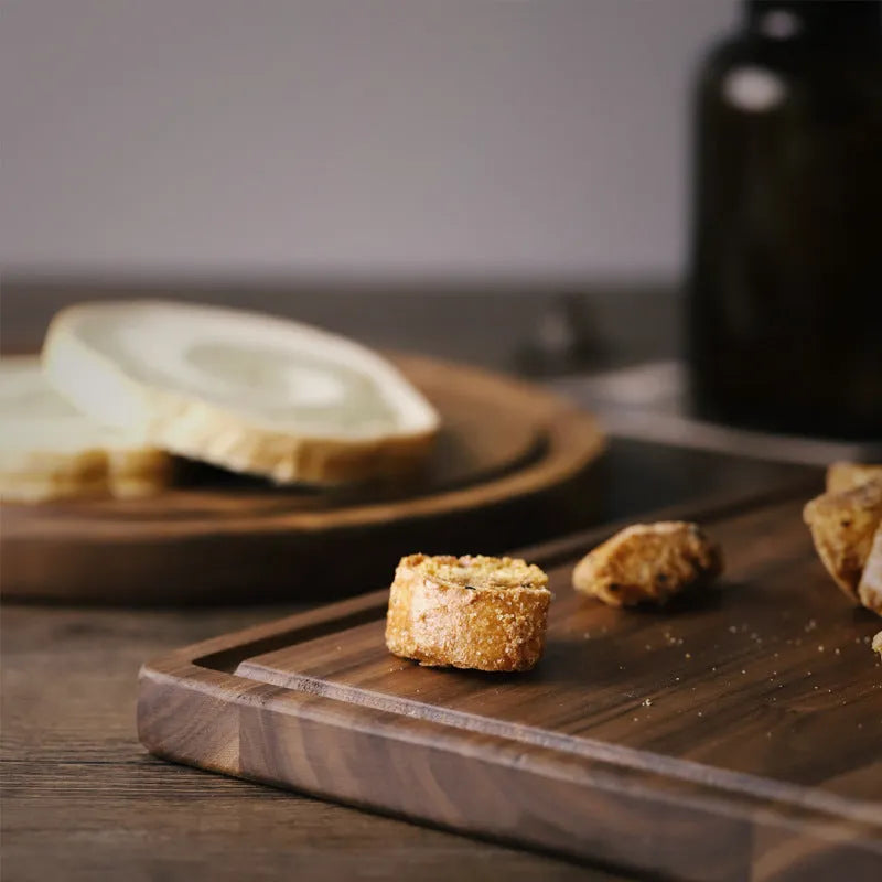 Black walnut wood cutting board with juice groove and side handle, shown in round and rectangular sizes.