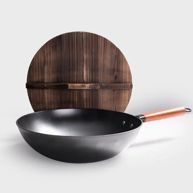 Black traditional cast iron wok pan with wooden handle and glass lid on induction hob