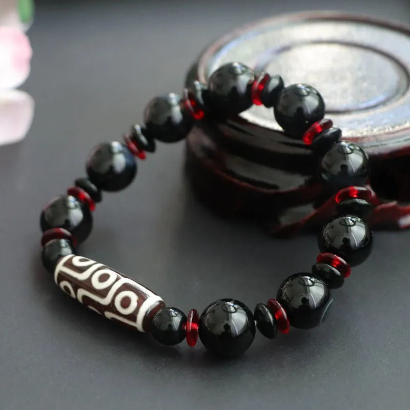 Hand-woven black agate dzi bead bracelet with 11mm geometric beads on a wrist.