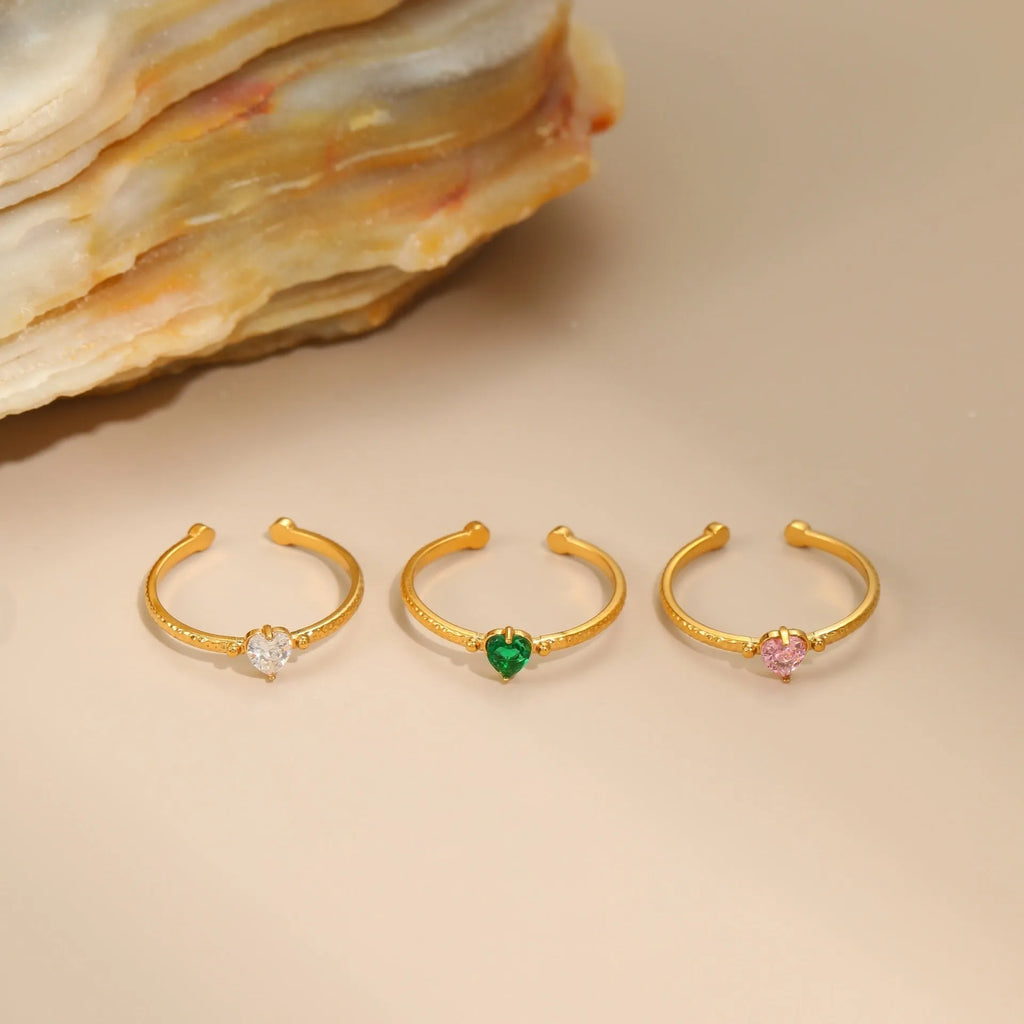 Open ended stainless steel ring with heart-shaped geometric centre and inlaid coloured zircon stone.