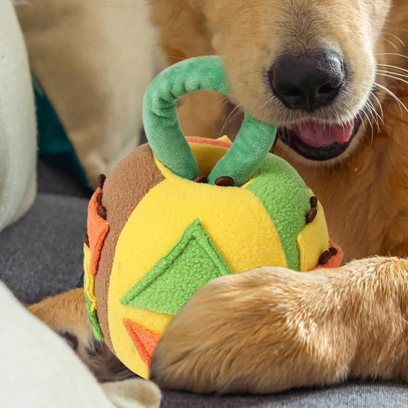 Green or pink polyester plush squeaky ball dog toy with treat pockets, shown next to a dog treat for scale.