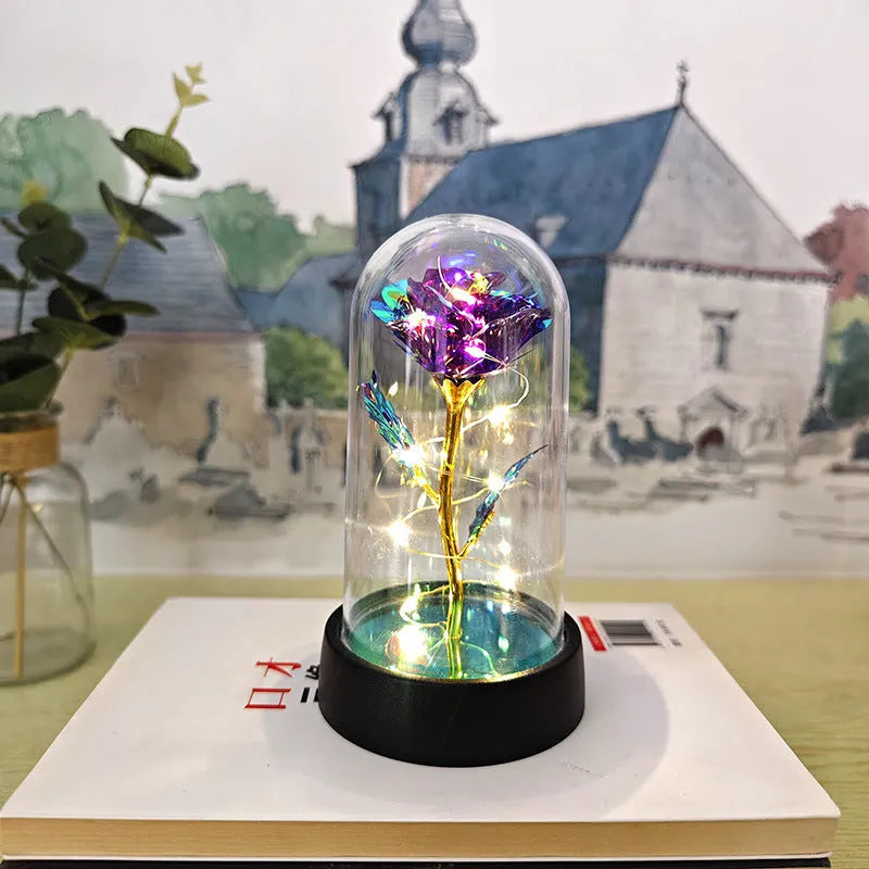 Small glass night lamp with plastic flowers on a black base.