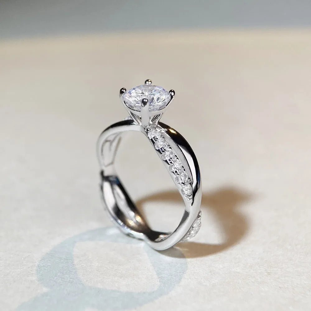 Close-up of a twisted sterling silver band moissanite ring with a four-claw setting and geometric lines.