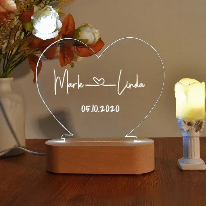 Personalised acrylic night light showing illuminated custom names and date on a transparent panel.