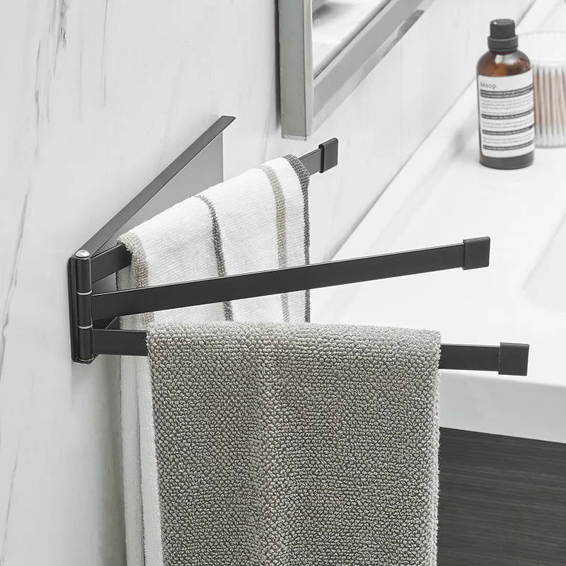 Black folding towel bar mounted on a bathroom wall with adhesive, shown in extended and folded positions.