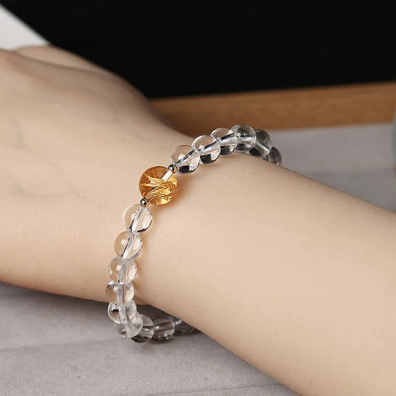 Unisex geometric bracelet with black obsidian, white crystal beads, and a golden dragon bead on a wrist.