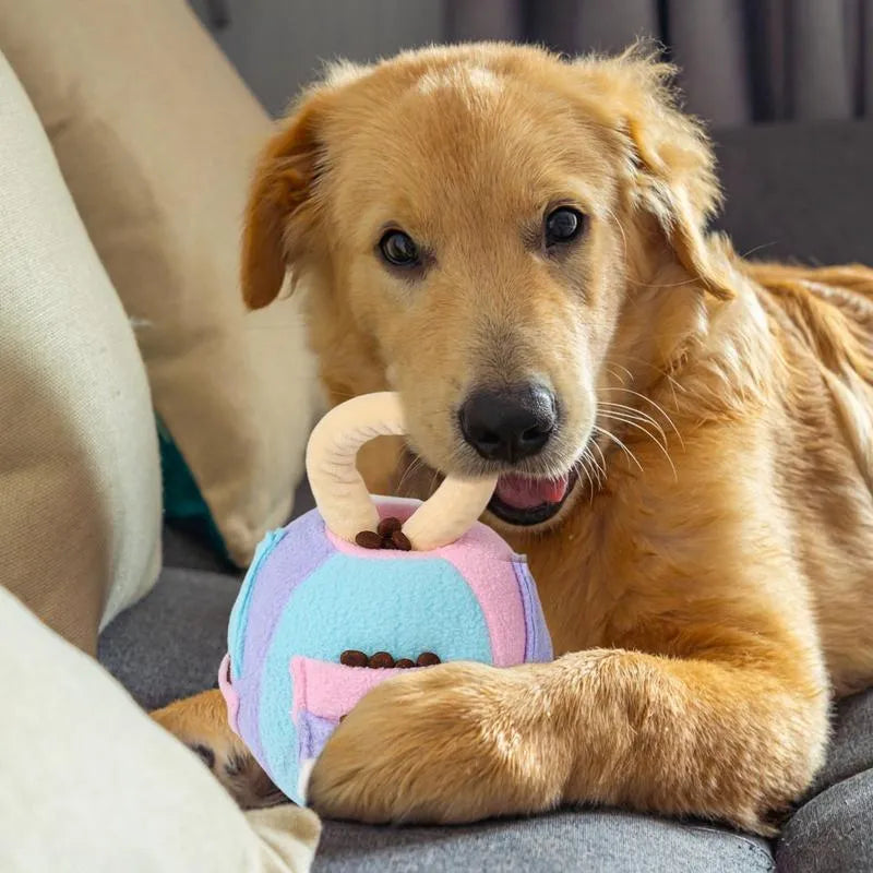 Green or pink polyester plush squeaky ball dog toy with treat pockets, shown next to a dog treat for scale.