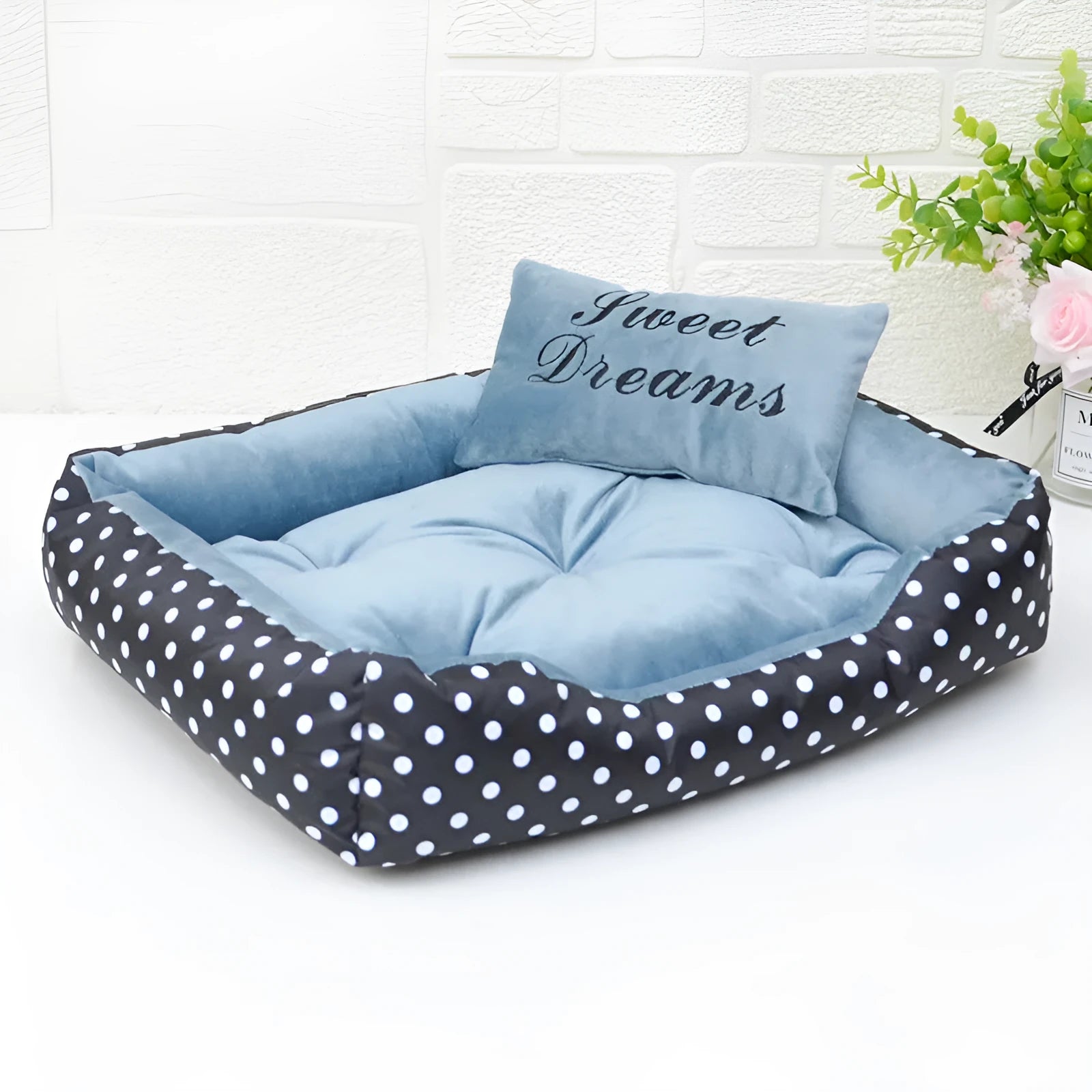 Polka dot printed cloth dog bed with matching embroidery pillow in grey, shown in a room setting.