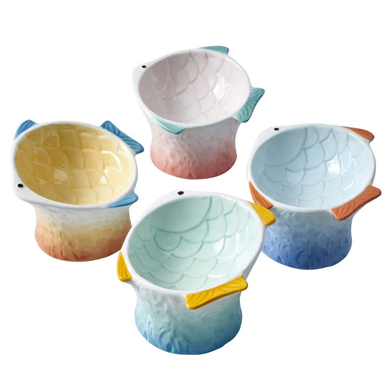 Blue fish-shaped ceramic cat bowl tilted at an angle on a table.