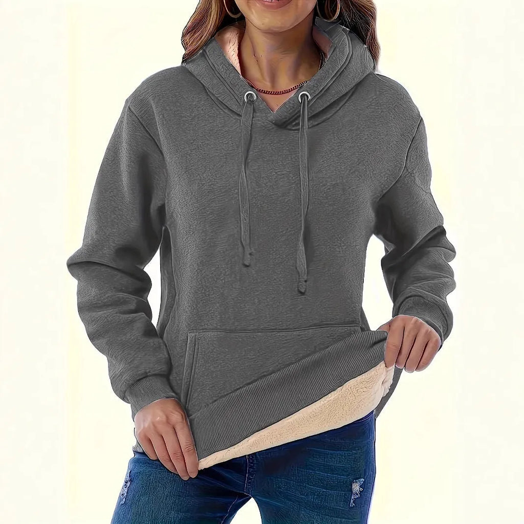 Woman wearing a loose black hooded sweater with a raised 3D pattern on the fabric.