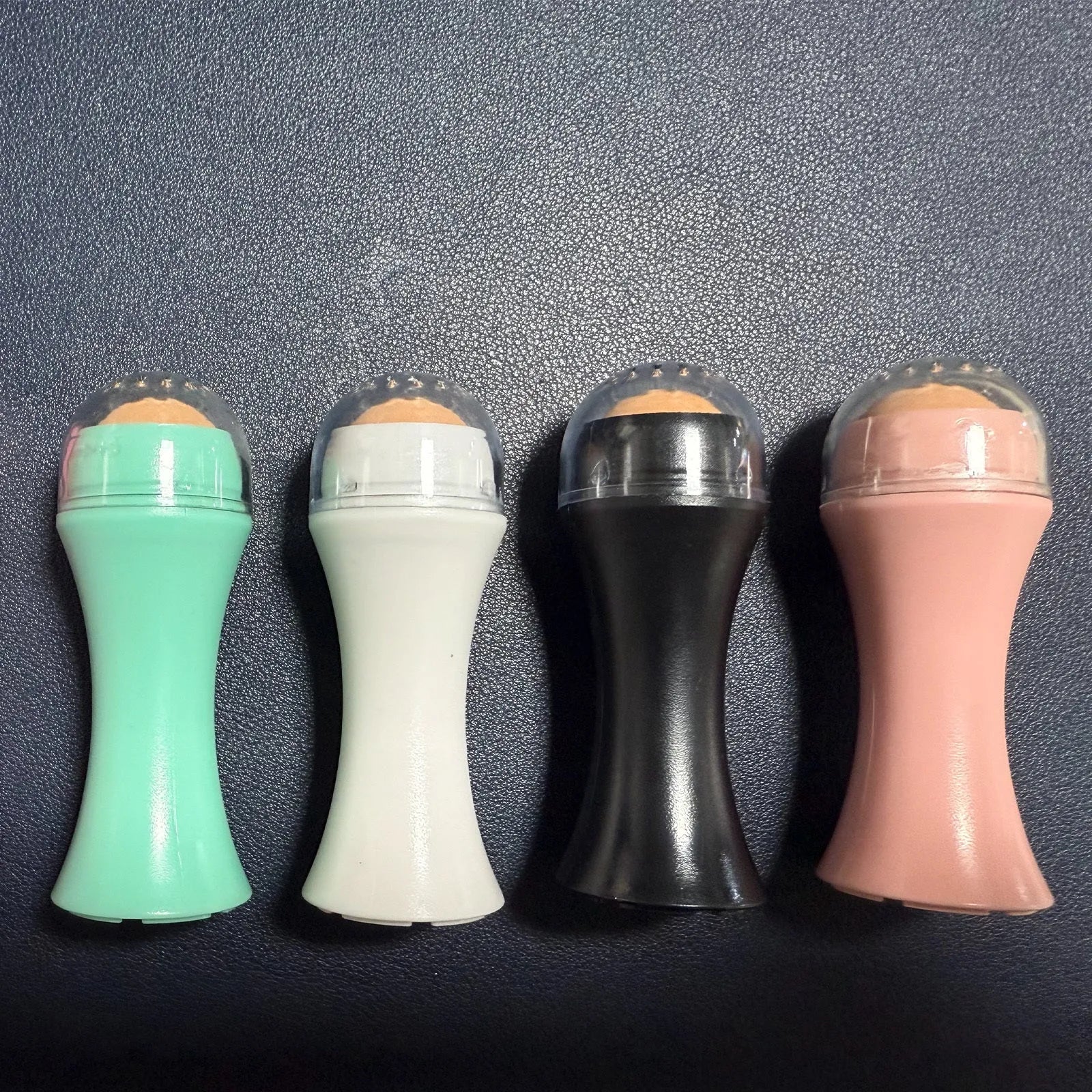 Volcanic stone facial roller for oily skin control in black, green, pink, or white colours