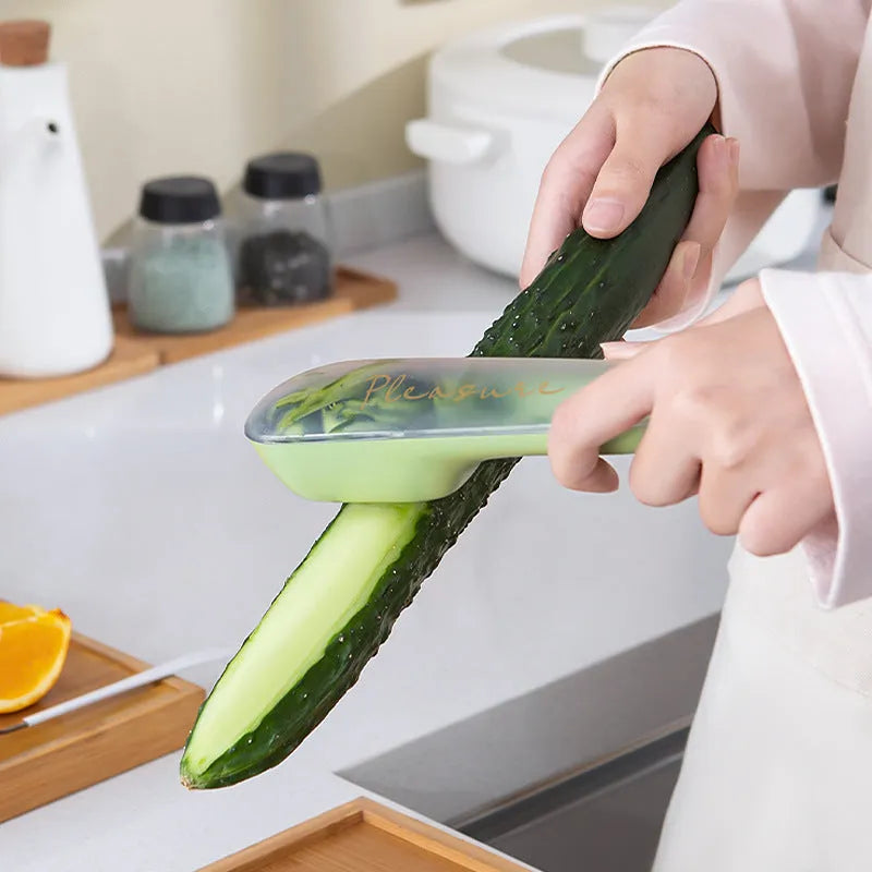 Dark green vegetable peeler with a storage tube and stainless steel blade on a kitchen worktop.