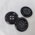 Assortment of large round plastic sewing buttons in multiple colours with four holes.