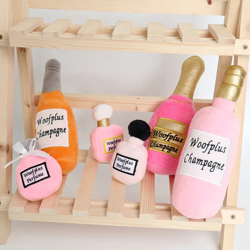 Green plush dog toy shaped like a wine bottle with a label, resting on a wooden floor.