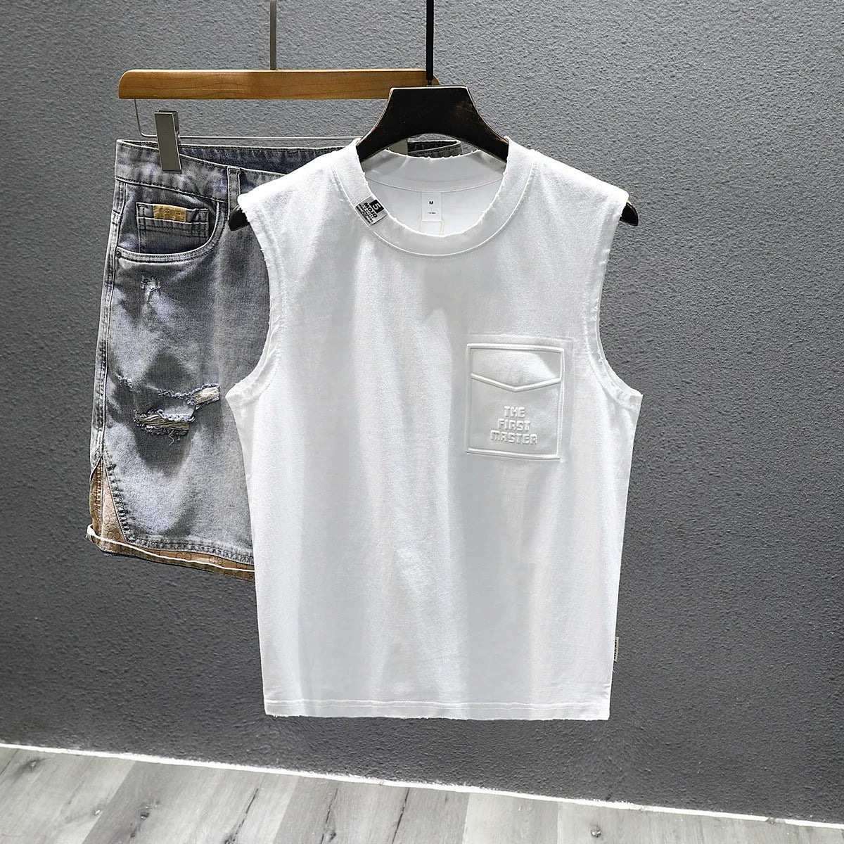 Loose fit solid colour cotton sleeveless t-shirt on a hanger, shown in white.