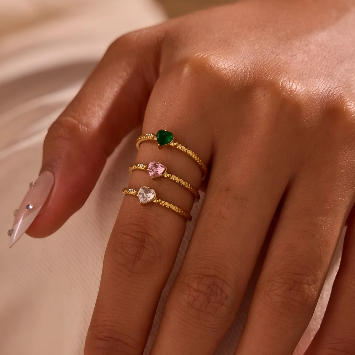 Open ended stainless steel ring with heart-shaped geometric centre and inlaid coloured zircon stone.
