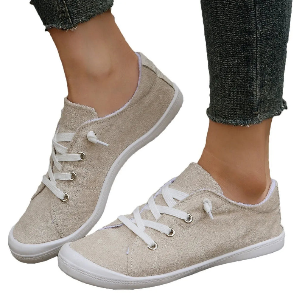 Women's creamy white beige fabric low-top casual sneakers with a rubber sole on a plain background.