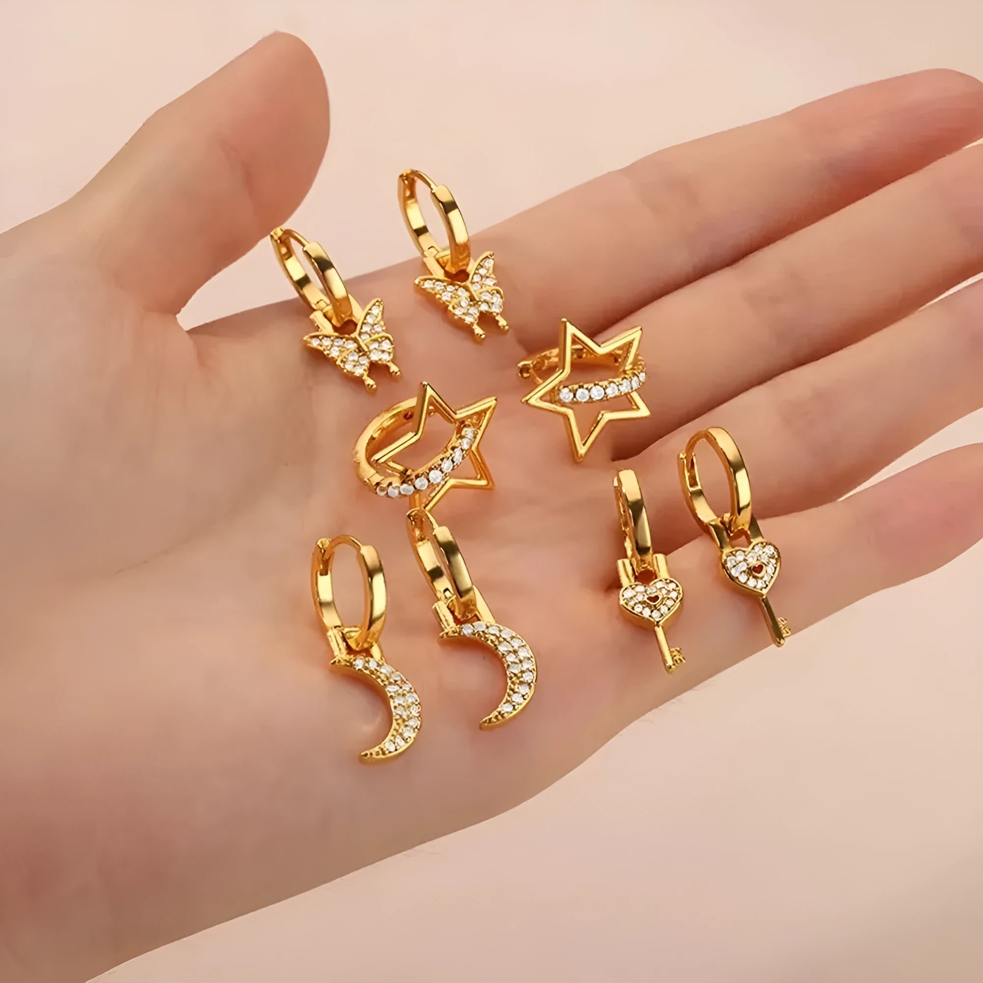 A pair of women's geometric butterfly earrings made from copper with heart, bow, and star shapes in a gold colour finish.
