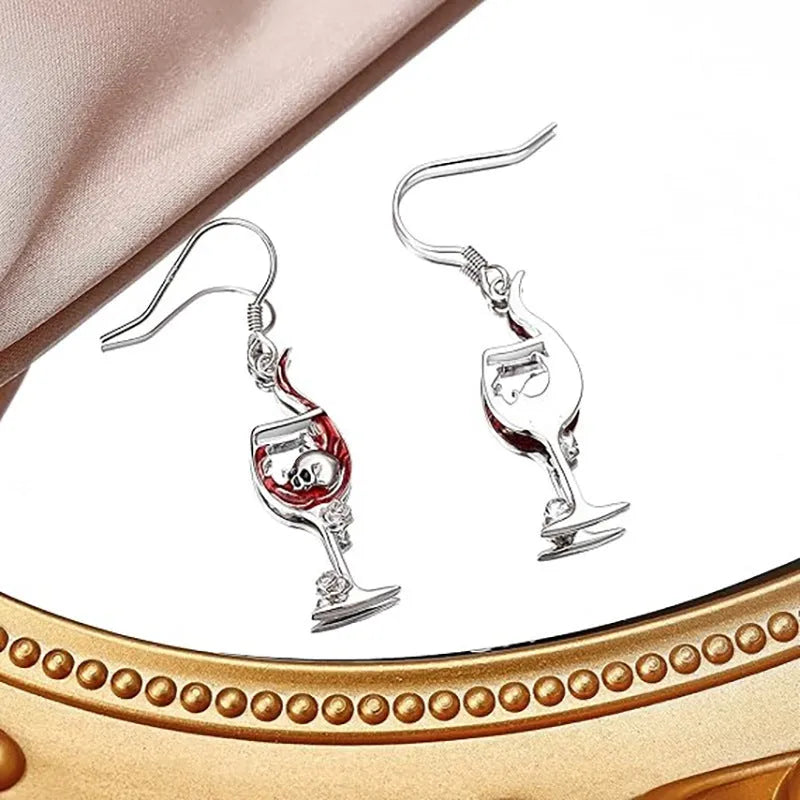 Pair of geometric drop earrings with combined skull and wine glass design in metallic finish.