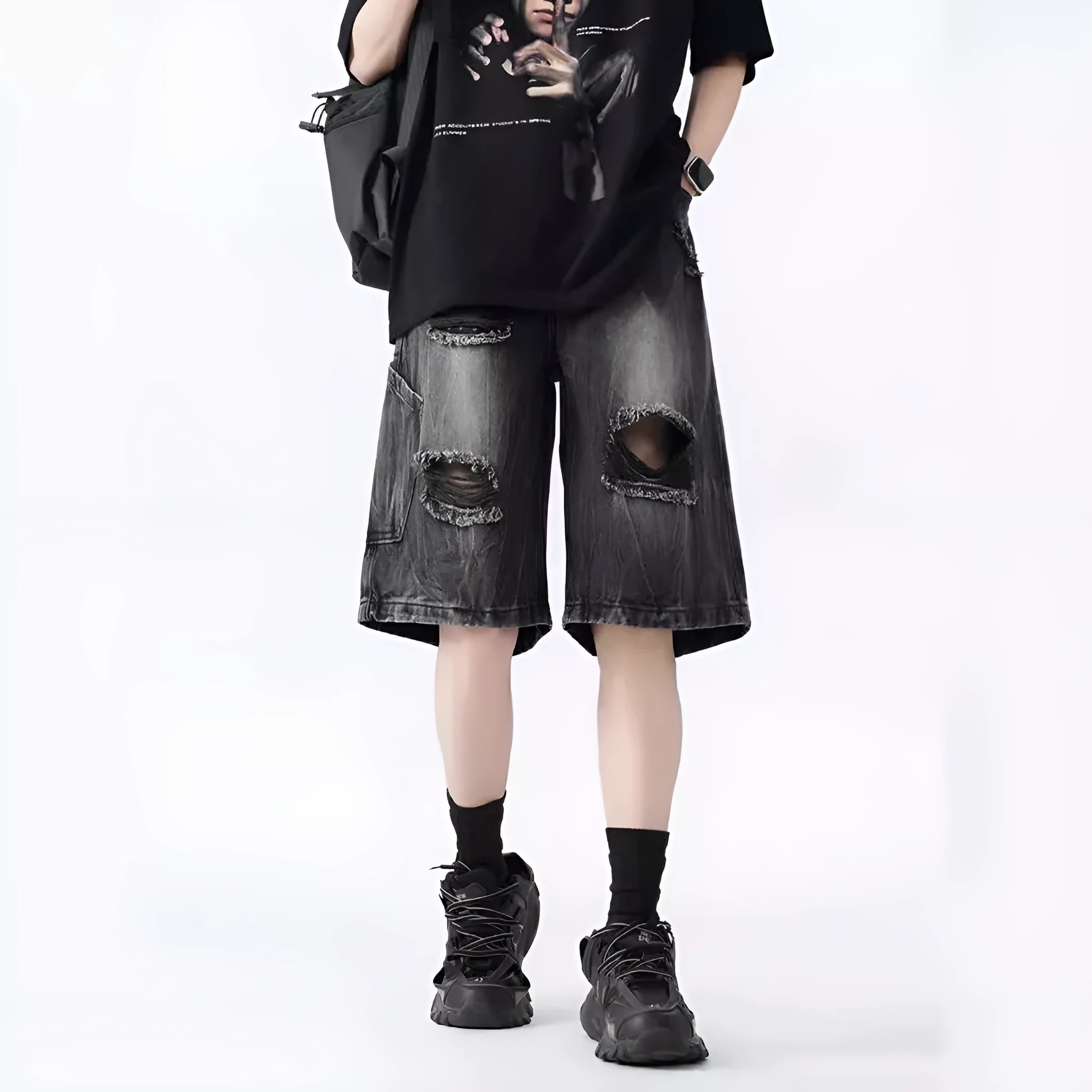 Man wearing black washed ripped denim shorts in a loose, retro style