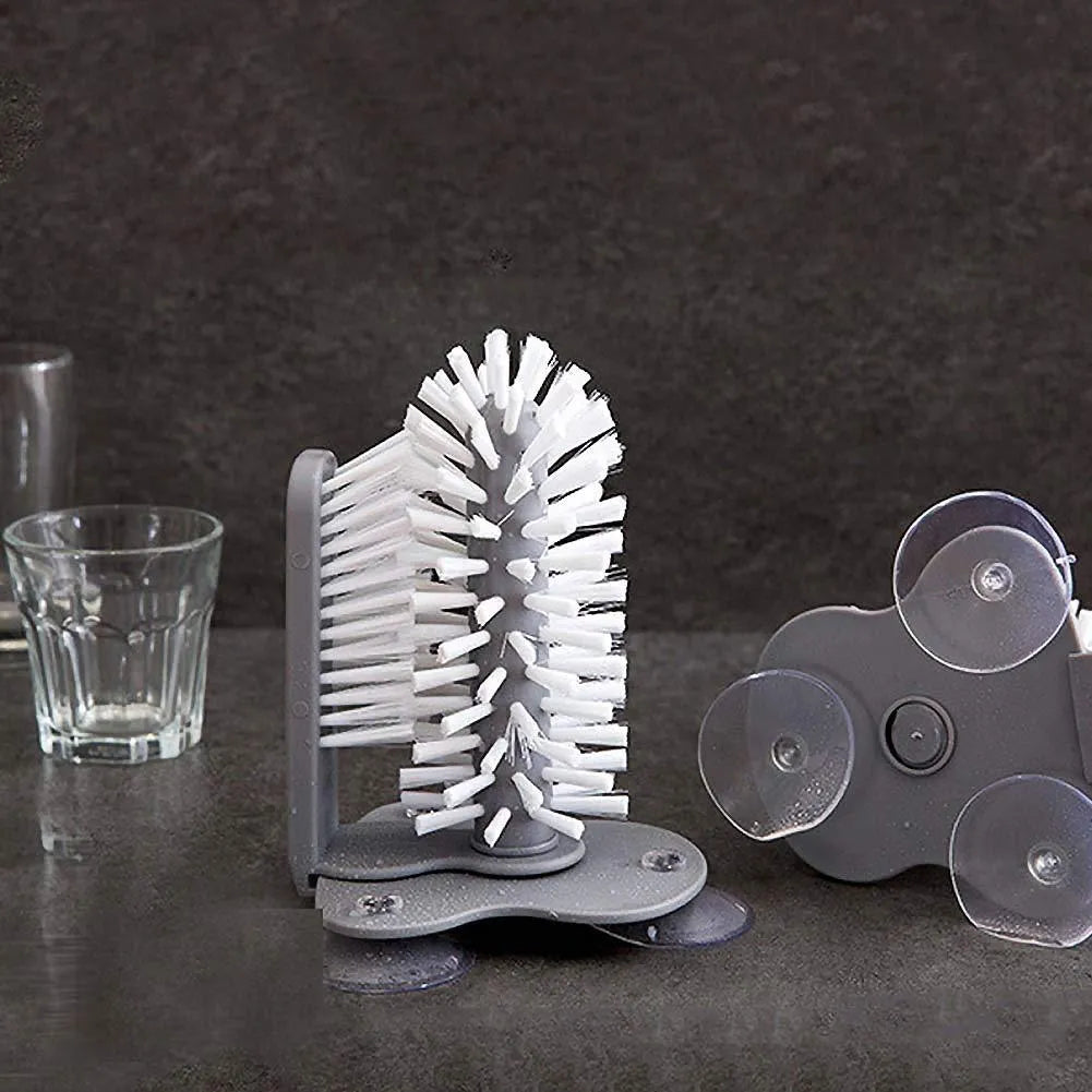 Grey 2 in 1 cup scrubber with double-sided bristles and three suction cups on the base for cleaning glassware.