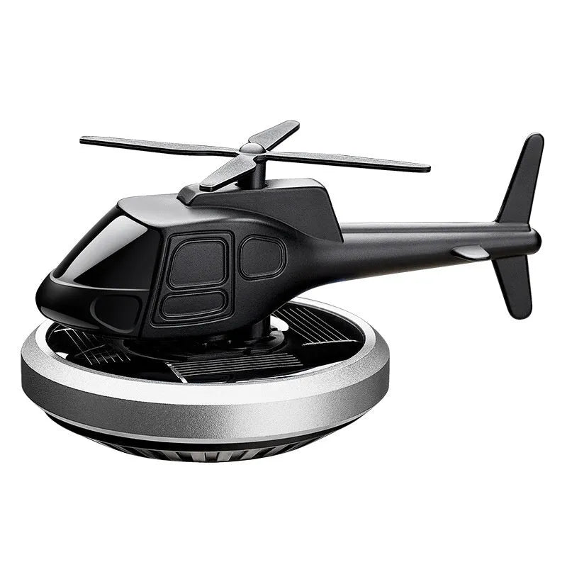 Silver metal solar helicopter car air freshener ornament with rotating blades on dashboard