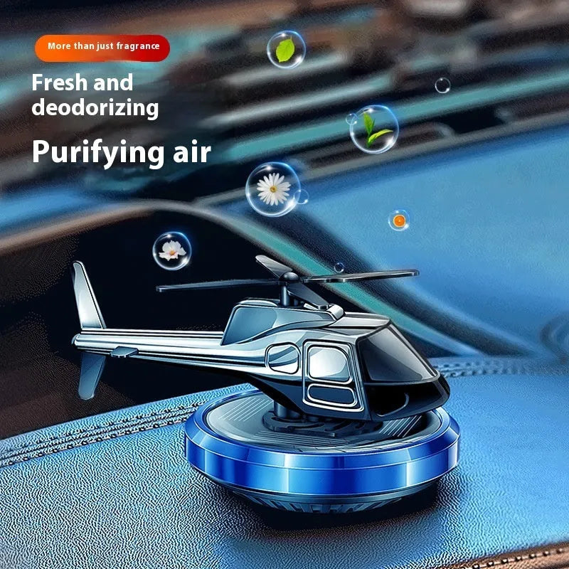 Silver metal solar helicopter car air freshener ornament with rotating blades on dashboard