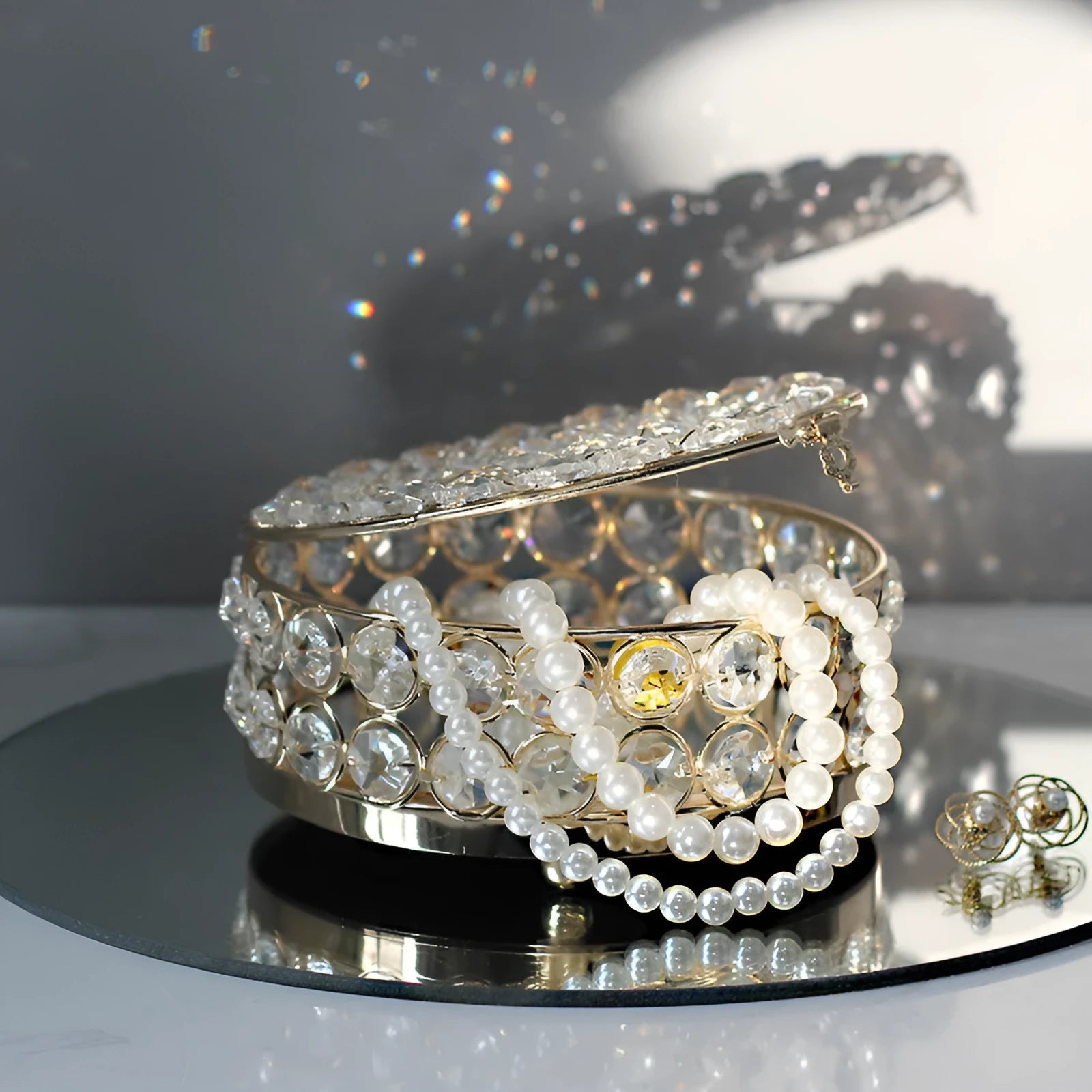 Transparent crystal glass jewelry box with a French gold metal frame on a table.