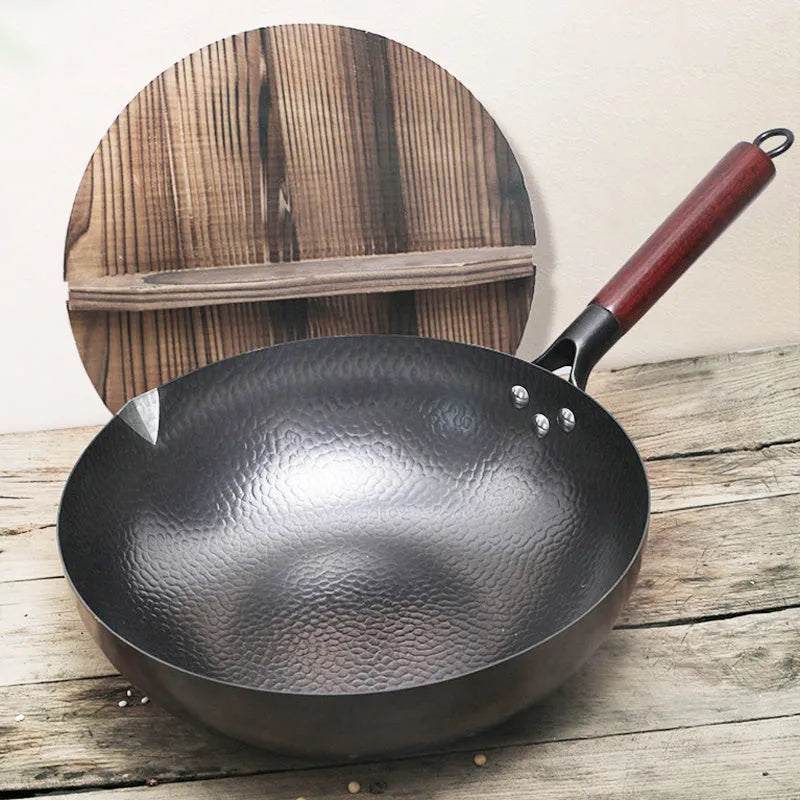 Black traditional cast iron wok pan with wooden handle and glass lid on induction hob