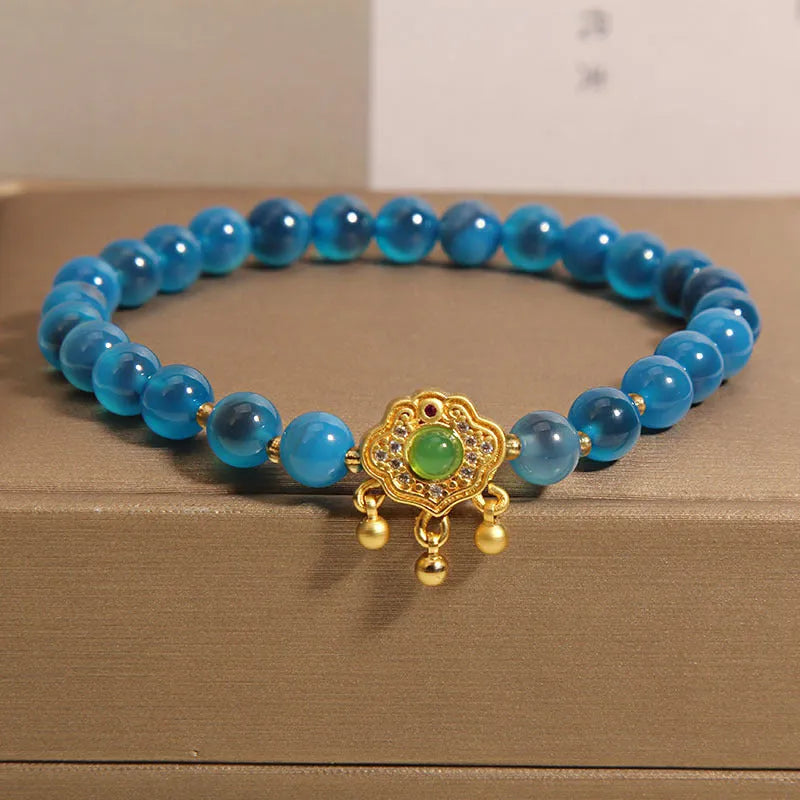 Close-up of a women's bracelet with a blue sugar heart agate safety lock pendant, crystal links, and rhinestone details.