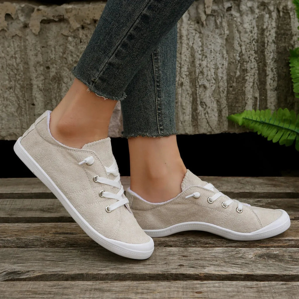 Women's creamy white beige fabric low-top casual sneakers with a rubber sole on a plain background.