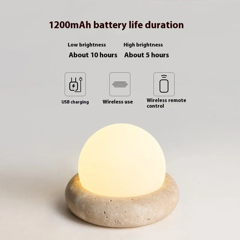 Cream-coloured modern bedside night light with remote control on a table.