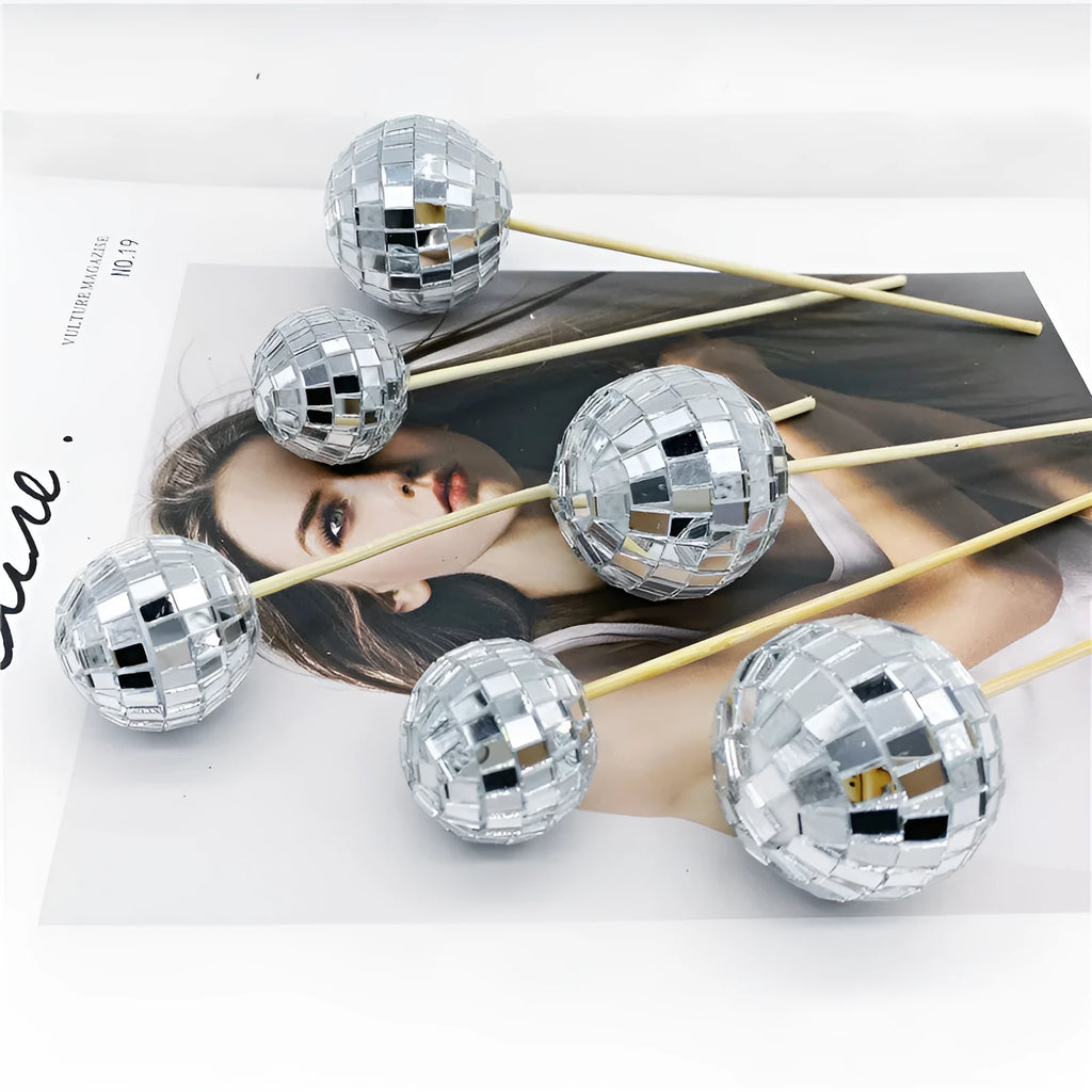 Glass disco ball cake decoration on wooden stick, showing reflective surface.