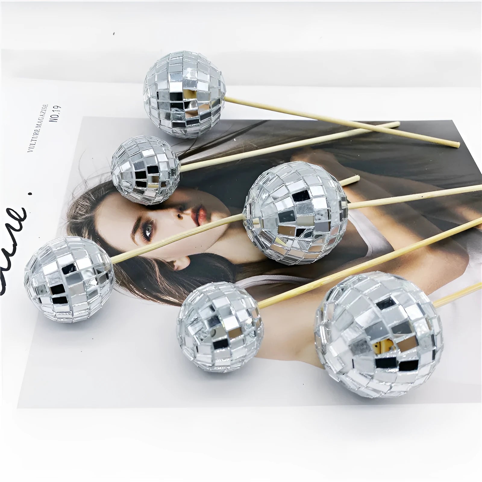Glass disco ball cake decoration on wooden stick, showing reflective surface.