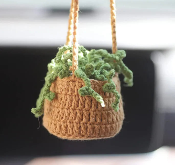 Green and white knitted wool car plant decoration basket with white hanging cord.
