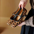 Women's black square toe ankle-strap stiletto heels with horse hair upper on wooden surface