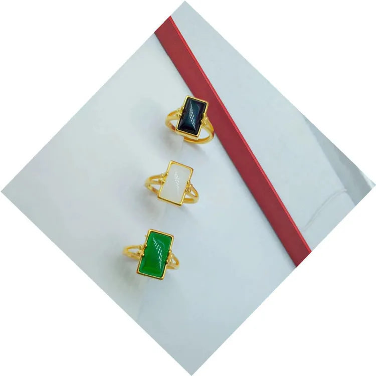 Adjustable brass gold-plated ring with a central electroplated gemstone, shown in black, green, and white colour options.