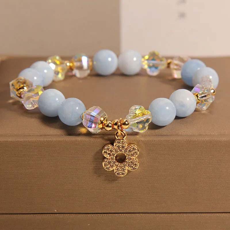 Women's aquamarine crystal bracelet with a four-leaf clover charm and pearl decorative elements.