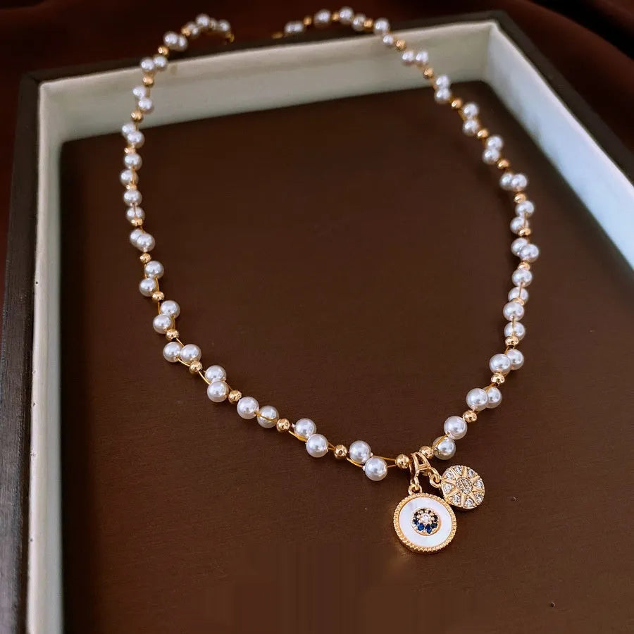 Gold electroplated women's necklace with round zircon and imitation pearl pendant on an adjustable clavicle chain.